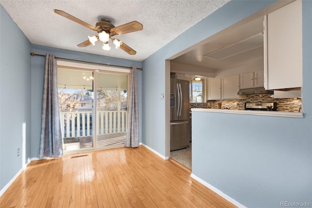 kitchen with under cabinet range hood, baseboards, ceiling fan, tasteful backsplash, and appliances with stainless steel finishes