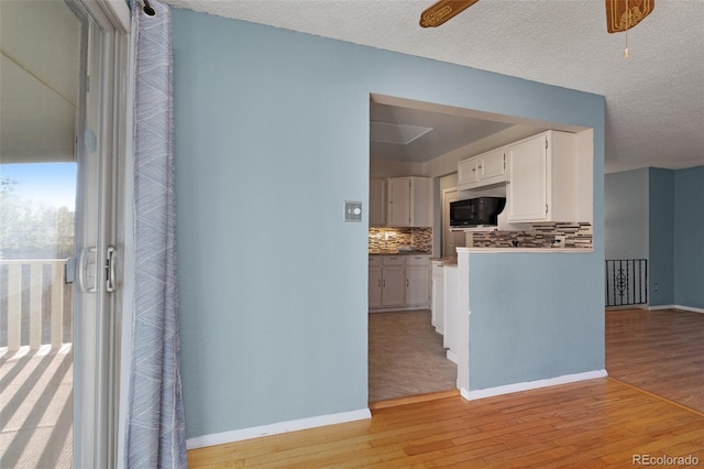 kitchen featuring light wood finished floors, baseboards, tasteful backsplash, and white cabinets