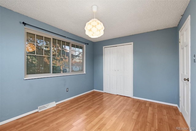 unfurnished bedroom featuring baseboards, visible vents, and wood finished floors