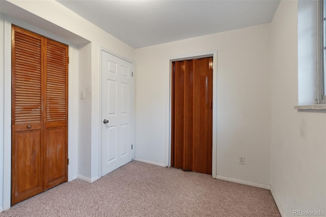 unfurnished bedroom featuring baseboards, light carpet, and a closet