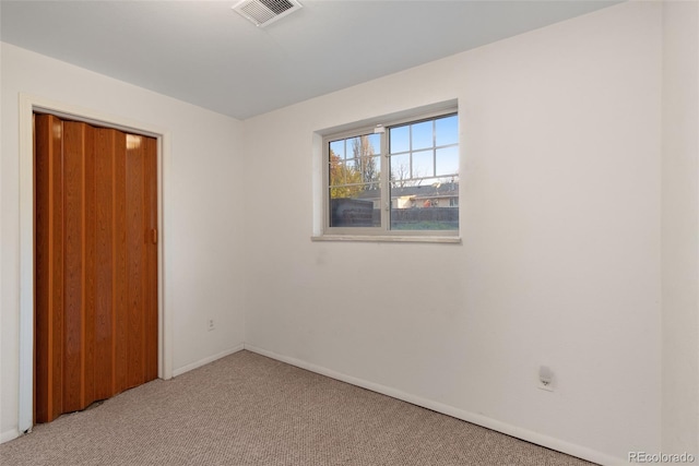 spare room with light colored carpet, baseboards, and visible vents