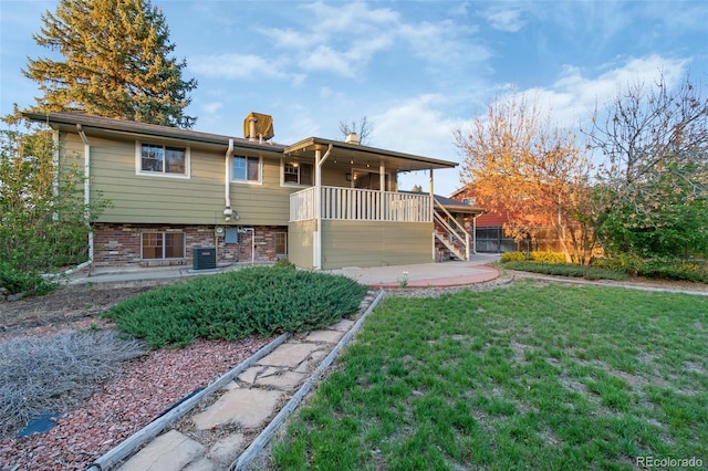 rear view of house featuring a yard, brick siding, cooling unit, a patio, and stairway