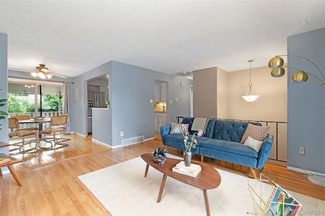 12642 E Ohio Ave, Aurora, CO 80012 - living area featuring wood finished floors, baseboards, a textured ceiling, and a ceiling fan