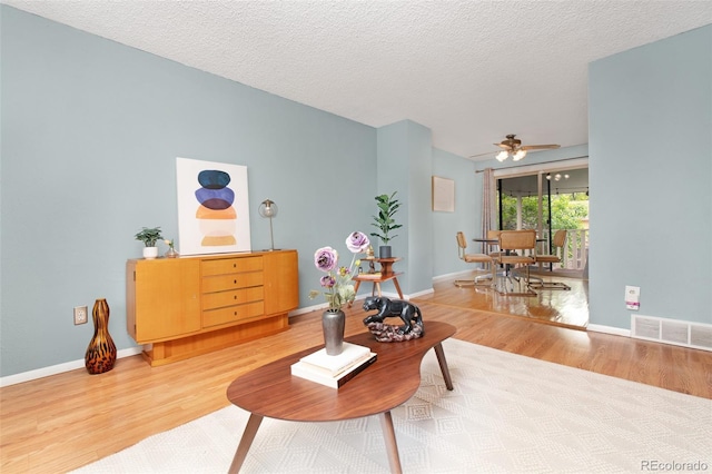 12642 E Ohio Ave, Aurora, CO 80012 - living area featuring light wood-type flooring, a ceiling fan, baseboards, and a textured ceiling