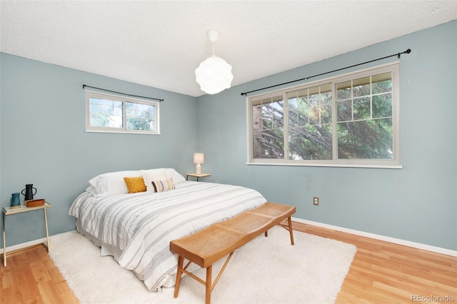 12642 E Ohio Ave, Aurora, CO 80012 - bedroom featuring wood finished floors, multiple windows, baseboards, and a textured ceiling