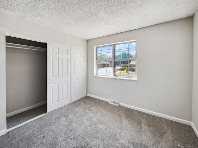 unfurnished bedroom featuring a textured ceiling, a closet, and carpet