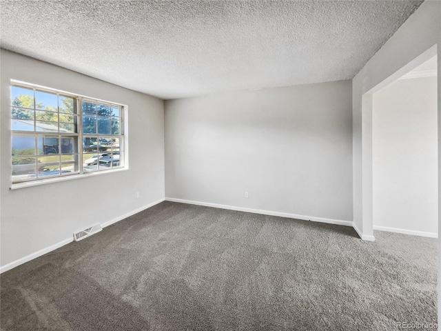 empty room with baseboards, visible vents, dark colored carpet, and a textured ceiling