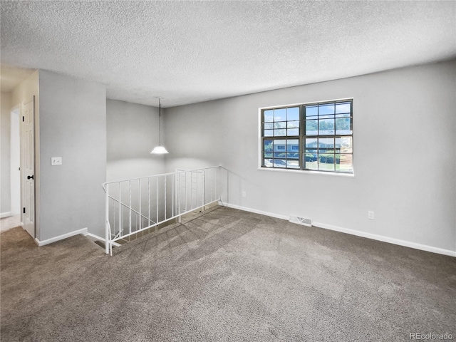 carpeted spare room with baseboards, visible vents, and a textured ceiling