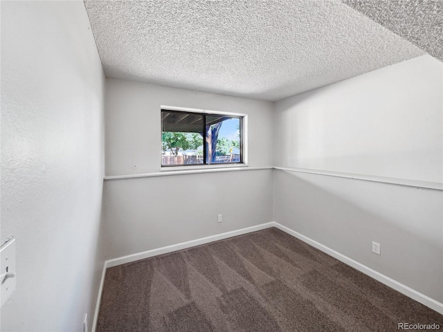 unfurnished room with carpet, baseboards, and a textured ceiling