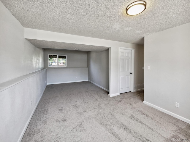 unfurnished room featuring a textured ceiling, carpet, and baseboards