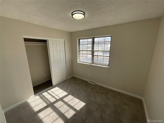 unfurnished bedroom with dark carpet, visible vents, and baseboards