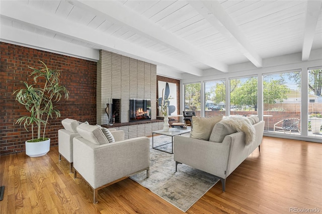8955 E 19th Ave, Aurora, CO 80010 - living room with light wood finished floors, beam ceiling, a fireplace, and brick wall