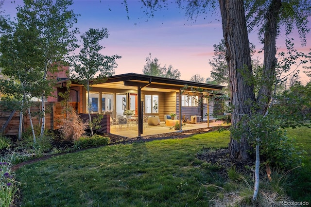 8955 E 19th Ave, Aurora, CO 80010 - back of property at dusk with a patio, a lawn, and a chimney