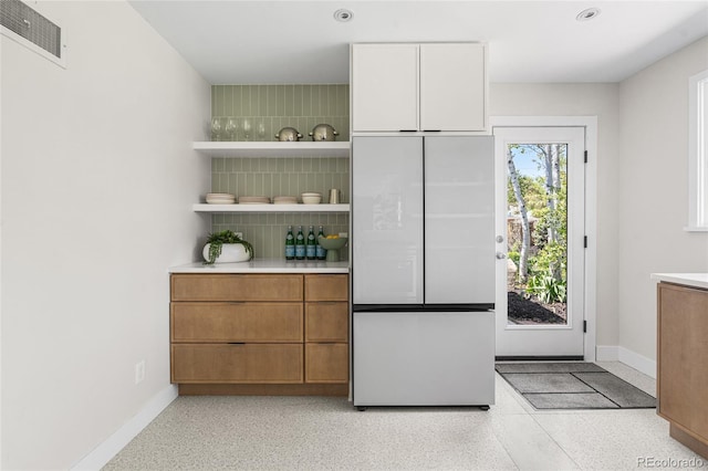 8955 E 19th Ave, Aurora, CO 80010 - bar featuring white refrigerator, dark aggregate flooring, baseboards, and decorative backsplash