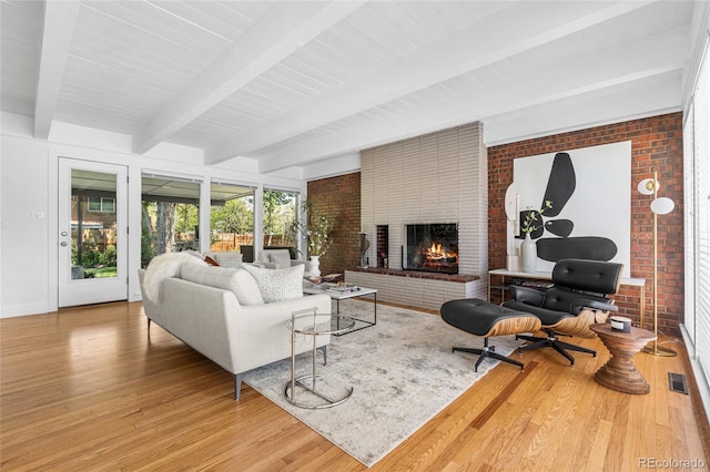 8955 E 19th Ave, Aurora, CO 80010 - living area featuring wood finished floors, brick wall, beam ceiling, and a fireplace