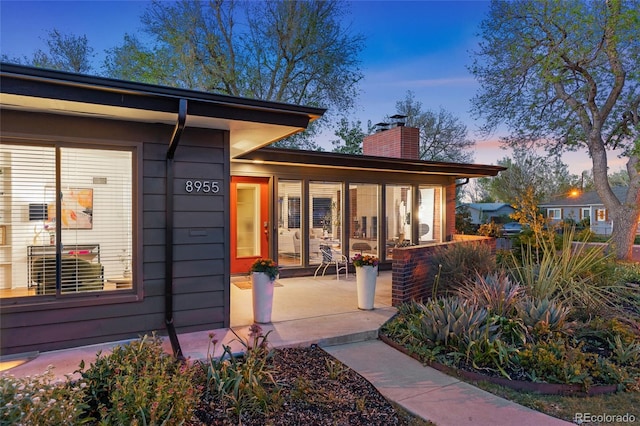 8955 E 19th Ave, Aurora, CO 80010 - exterior entry at dusk with a chimney