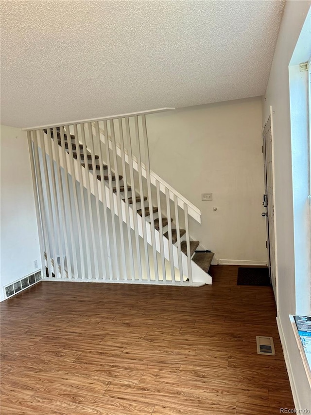 staircase with a textured ceiling and hardwood / wood-style flooring