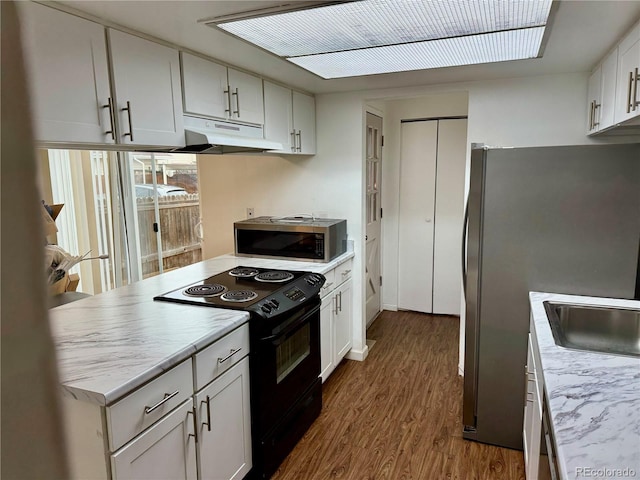 kitchen with hardwood / wood-style floors, appliances with stainless steel finishes, white cabinetry, and sink