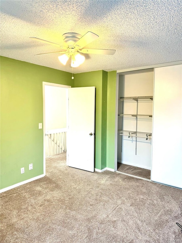 unfurnished bedroom with a textured ceiling, ceiling fan, carpet flooring, and a closet