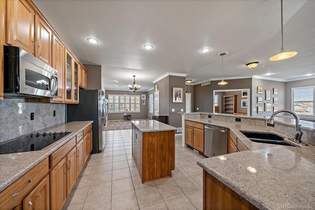 kitchen featuring decorative light fixtures, a sink, a kitchen island, appliances with stainless steel finishes, and glass insert cabinets