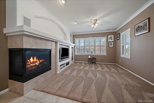 unfurnished living room with ceiling fan, a tile fireplace, light carpet, baseboards, and crown molding