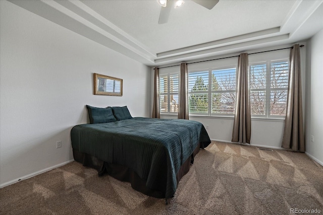 carpeted bedroom featuring ceiling fan, a tray ceiling, and baseboards