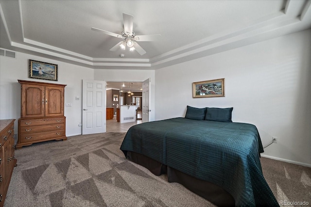 carpeted bedroom featuring visible vents, a tray ceiling, ceiling fan, and baseboards