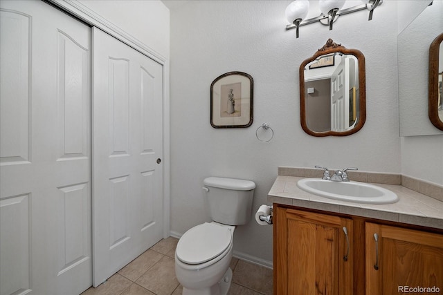 half bath featuring toilet, tile patterned flooring, a closet, and vanity