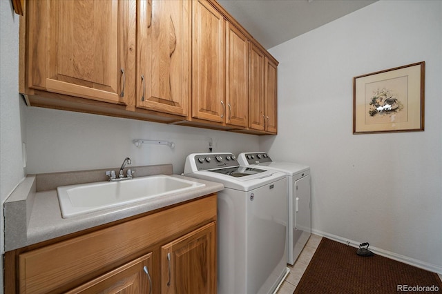 laundry room with washer and clothes dryer, cabinet space, light tile patterned flooring, a sink, and baseboards