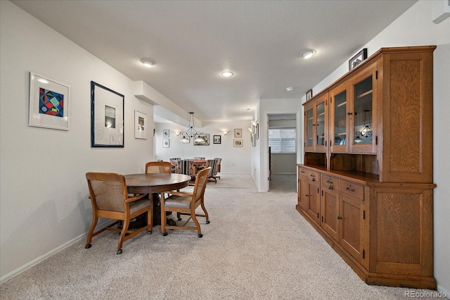 dining space with light colored carpet, a notable chandelier, and baseboards