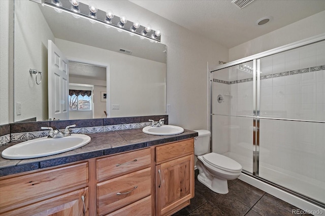 bathroom featuring double vanity, a sink, toilet, and a shower stall