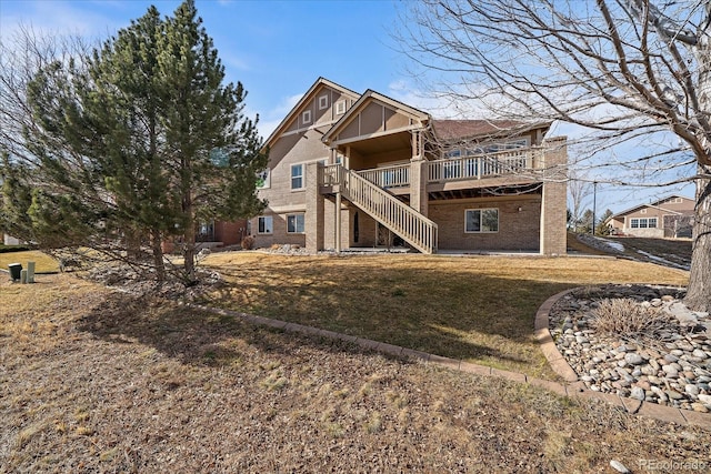 rear view of house with a deck, a yard, brick siding, and stairway