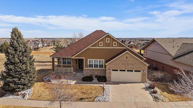 view of front of house with driveway, a residential view, covered porch, cooling unit, and brick siding