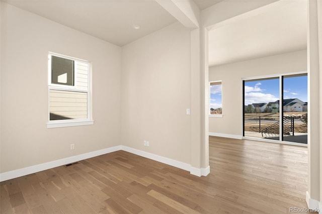 unfurnished room featuring beam ceiling and light hardwood / wood-style floors