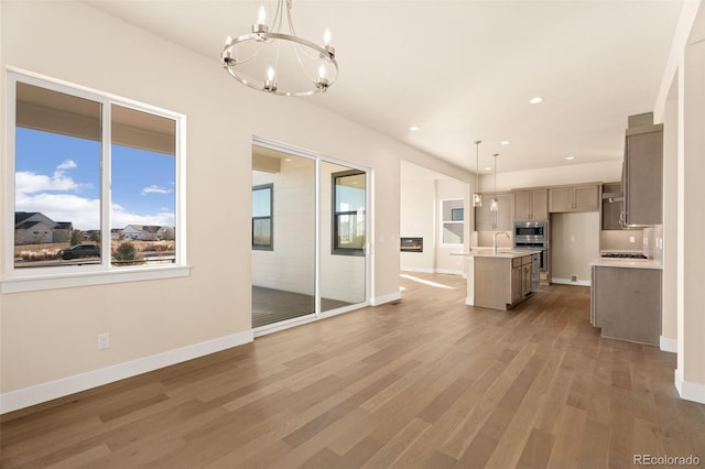 kitchen featuring appliances with stainless steel finishes, a chandelier, decorative light fixtures, dark hardwood / wood-style flooring, and an island with sink