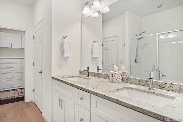 bathroom featuring hardwood / wood-style floors, vanity, and a shower with door