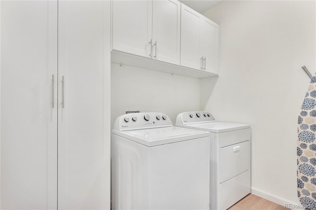 clothes washing area with separate washer and dryer, cabinets, and light hardwood / wood-style floors