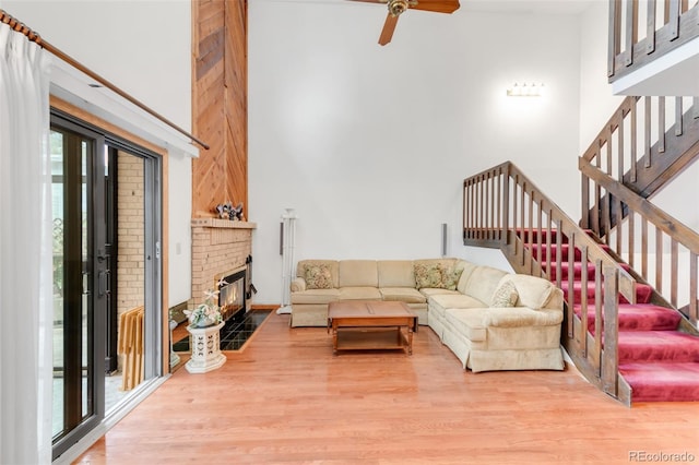 4034 S Atchison Way, Aurora, CO 80014 - living area featuring wood finished floors, stairs, a ceiling fan, a brick fireplace, and a towering ceiling