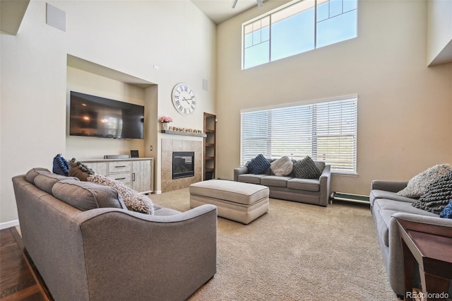 living room featuring a tiled fireplace and a high ceiling