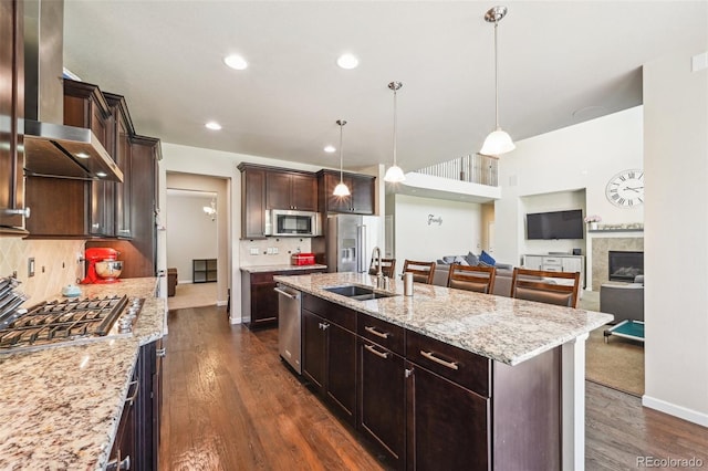 kitchen featuring pendant lighting, backsplash, an island with sink, and appliances with stainless steel finishes