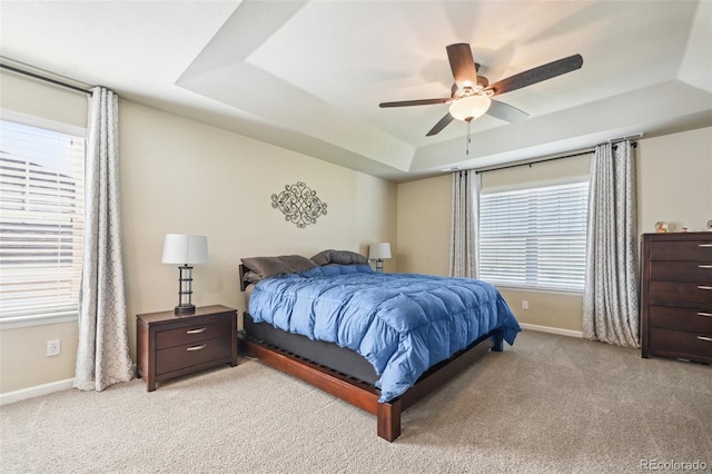 bedroom with light carpet, a raised ceiling, and ceiling fan