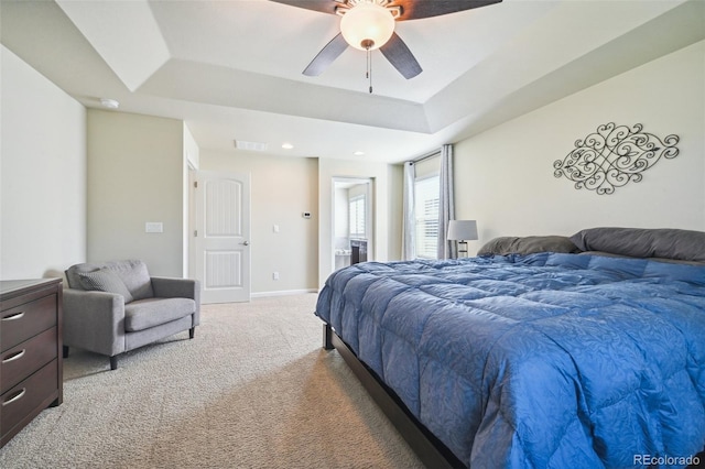 carpeted bedroom with ceiling fan and a tray ceiling