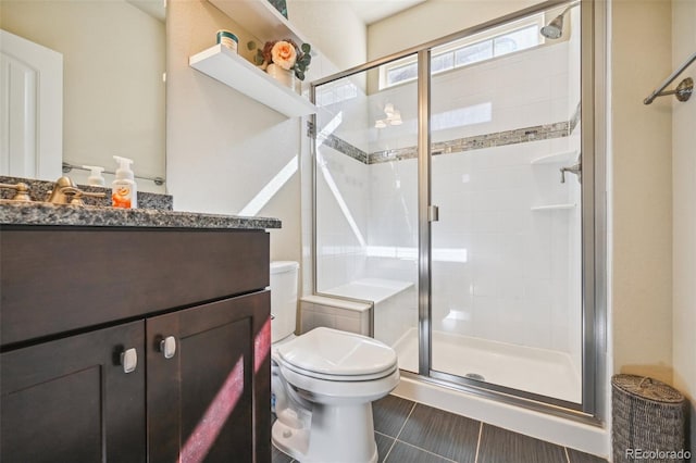 bathroom with vanity, a shower with shower door, tile patterned floors, and toilet