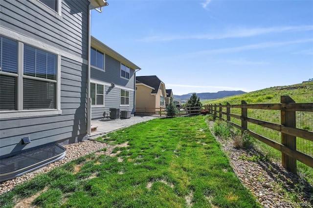 view of yard with a patio, a mountain view, and central AC unit