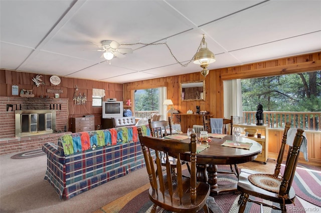 307 Virginia Rd, Bailey, CO 80421 - dining area with carpet flooring, wood walls, a ceiling fan, and a brick fireplace