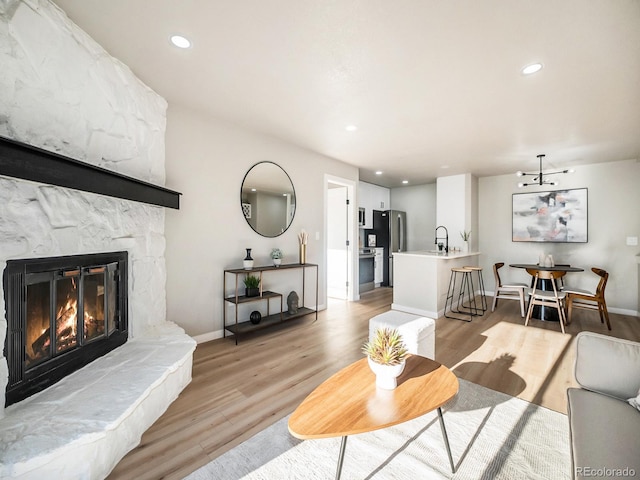 living room with sink, light hardwood / wood-style flooring, and a fireplace