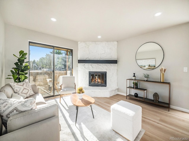 living room featuring a stone fireplace and light hardwood / wood-style floors