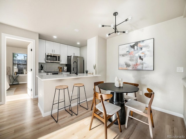 dining room with light hardwood / wood-style floors and a notable chandelier