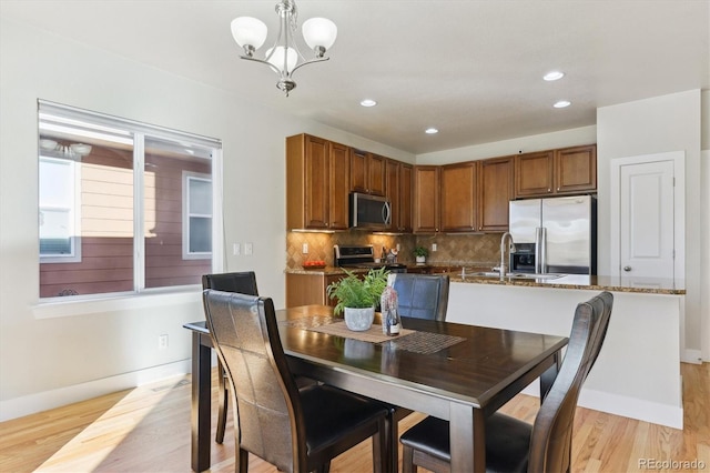 dining area with light hardwood / wood-style floors, a notable chandelier, and sink