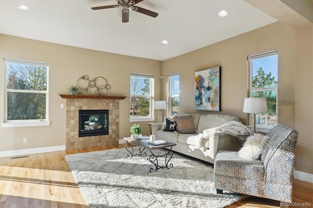 living room with hardwood / wood-style floors, ceiling fan, plenty of natural light, and a fireplace